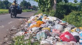 Seorang pengendara sepeda motor melintasi tumpukan sampah di Desa Rempanga
