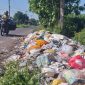 Seorang pengendara sepeda motor melintasi tumpukan sampah di Desa Rempanga
